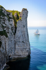 A sailing ship is cruising off the Aval cliff in Etretat, France