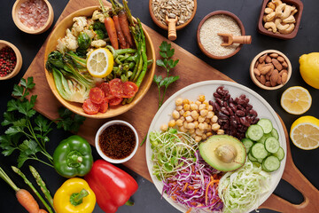 Fototapeta na wymiar Vegan protein source. Buddha bowl dish, avocado, pepper, tomato, cucumber, red cabbage, chickpea, fresh lettuce salad and walnuts, nuts, beans, . Healthy vegetarian eating, super food. Top view.