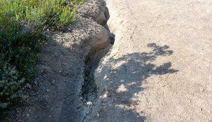 A dried up stream with white dried earth on a hillside on a clear summer day