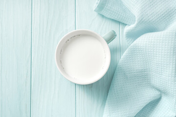 Blue mug of fresh milk on a wooden table. Top view of milk on a blue background