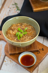 Braised fish maw soup in red gravy with mushroom crab meat on wooden board