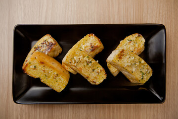 Tasty bread with garlic, cheese and herbs on kitchen table