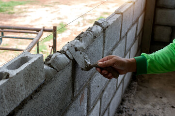 masonry worker make concrete wall by cement block and plaster at construction site