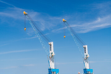 Fototapeta na wymiar Two cranes are used to transport goods in large port industries. sky backdrop