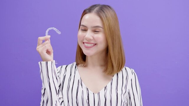 Young smiling woman holding invisalign braces in studio, dental healthcare and Orthodontic concept..