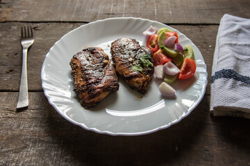 Close up of Chicken steak and vegetables in a white plate on a wooden background with use of selective focus