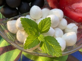 A sprig of mint decorates white mozzarella balls in the rays of the setting sun.