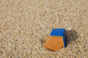 Fototapeta na wymiar 砂の上で傾く家のミニチュア 