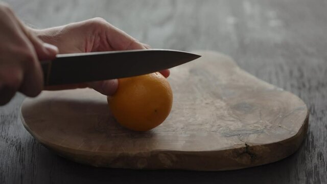 Man cutting sweet lemon on olive wood board