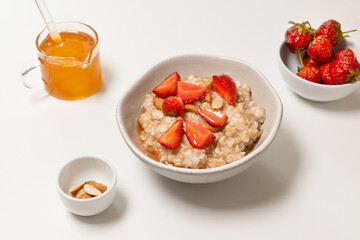 Bowl of oatmeal porridge with strawberry and almond flakes on table. Healthy lifestyle, healthy eating, dieting concept