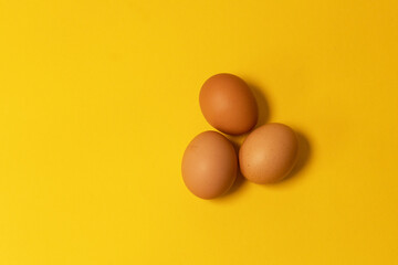 Easter brown chicken eggs on yellow background. Top view, flat lay, copy space.
