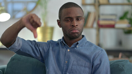 Young African Man with Thumbs Down at Home 