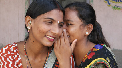 Closeup shot of two South Asian women smiling and gossiping about something
