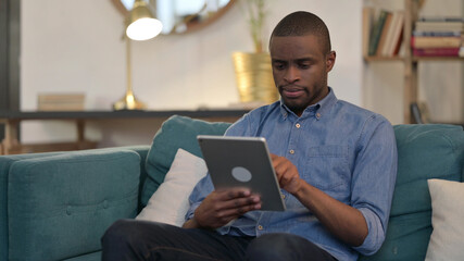 Young African Man using Tablet on Sofa 
