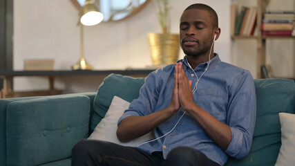 Spiritual Young African Man Meditating on Sofa