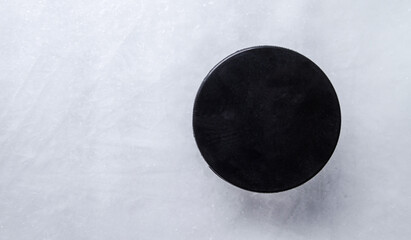 Black hockey puck on the ice rink.