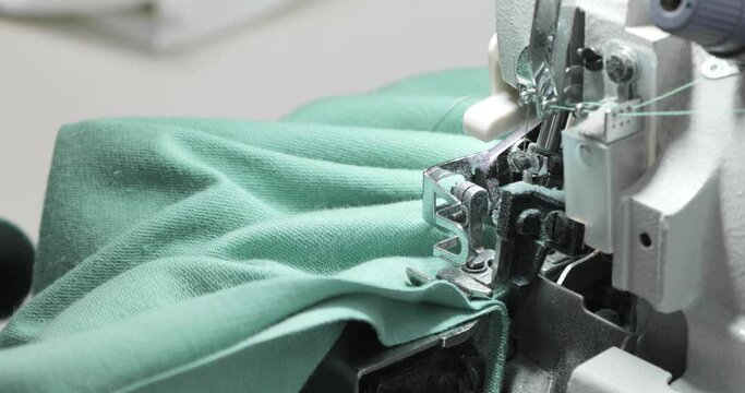 Overlock Sewing Machine. Female hands working on Tailoring. Automated industrial Textile Sewing machine. Close-up.