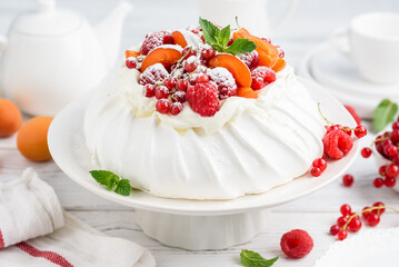 Pavlova cake decorated with fresh raspberries, apricots and red currants. Summer dessert. Selective focus