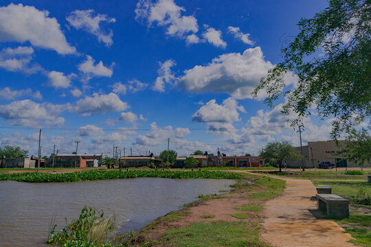parque al aire libre con lugar para sentarse al costado de una laguna artificial, Castelli - Chaco - Argentina