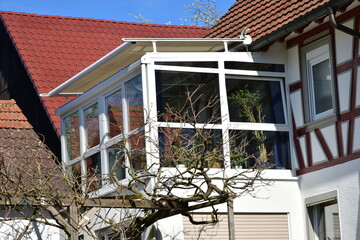 Wintergarten mit dreiseitiger Verglasung und eingebauter Markise an einem Wohnhaus