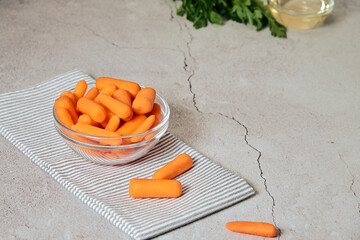 nature, diet and healthy food concept - view of fresh baby peeled carrots and glass of water and oil and herbs on the background. Copy space