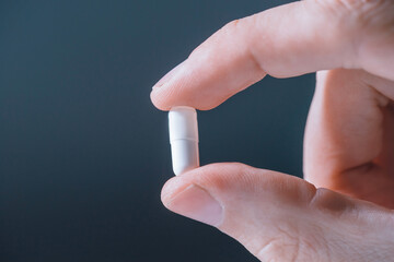 close up. white pill in his hand .