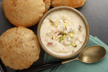 Shrikhand & Puri, Shrikhand is an Indian sweet dish made of strained curd,garnished with dry fruits and saffron. Served in a ceramic bowl & plate with Puri, Deep fried flat bread.Selective focus
