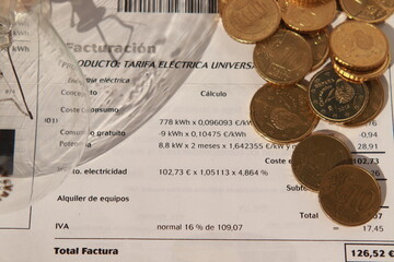 Factura de la luz con sombra de una bombilla y monedas