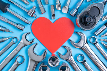 Red heart surrounded by various wrenches and other auto tools. Greeting card concept for car owners