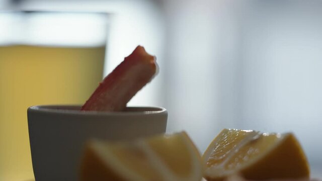 Slow motion gimbal shot of crab leg meat on a olive board with sweet lemon and dip sauce on concrete countertop