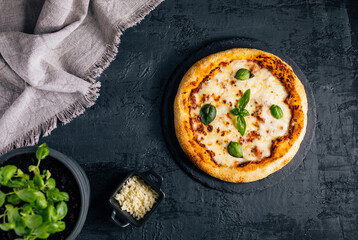 Traditional Margherita Pizza with basil, tomato, olive oil, mozzarella on a rustic background