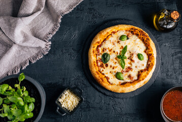 Traditional Margherita Pizza with basil, tomato, olive oil, mozzarella on a rustic background