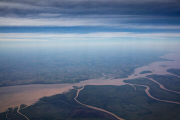 Flying. Aerial view of the Amazon river, streams and tributary channels flowing across the green tropical rainforest and field, under a beautiful blue sky.  - obrazy, fototapety, plakaty