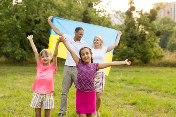 Obraz premium Happy family s with flag of Ukraine in field.