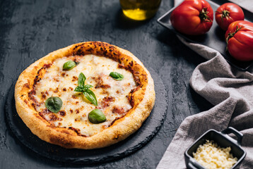 Traditional Margherita Pizza with basil, tomato, olive oil, mozzarella on a rustic background