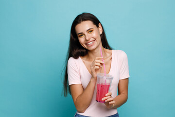 Young girl drinking fresh juice from plastic cup take-out food. Woman with berry lemonade on blue background. Summer cold drinks.