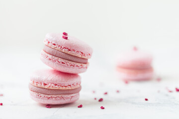 Pink macaroons with shallow depth of field on the white background. French sweet dessert cookies with red petals.
