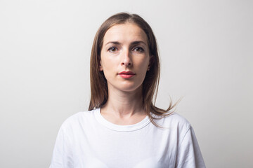 Fototapeta premium Young woman in a white T-shirt on a light background