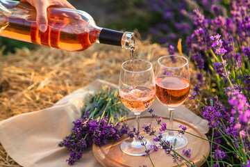 A woman holds wine in glasses. Picnic in the lavender field. Selective focus.
