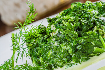 Cooked spinach with garlic on a white plate. Vegetarian food.