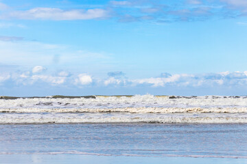 Landscape with ocean waves under blue sky.