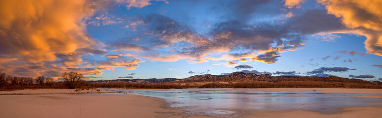 Winter Sunset at Chatfield - A colorful panoramic sunset view of frozen Chatfield Reservoir, with rolling hills of Front Range at horizon. Chatfield State Park, Denver-Littleton, Colorado, USA.