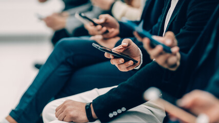 group of diverse young people with smartphones sitting in a row
