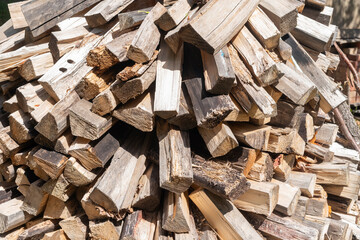 Chopped firewood stacked in a woodpile, background.