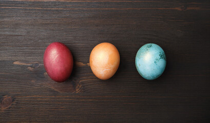 Three Easter eggs on wood table background. Flat lay.