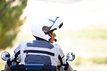 Vista trasera de motociclista mirando lateralmente con casco integral abierto sobre fondo...