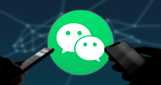 Zwei Personen Halten Smartphone In Der Hand, Im Hintergrund Das WeChat Logo, Chat-Dienst, Mobile Payment, China