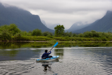 Adventure Adult Man Kayaking in Blue Kayak surrounded by Canadian Mountain Landscape. Taken in Widgeon Valley, Pitt Meadows, Vancouver, British Columbia, Canada.