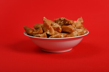 Horizontal shot of plate full of fresh traditional luxurious Arabian handmade Brewat sweets, isolated on red background. Arabic traditional oriental sweets on the festive table