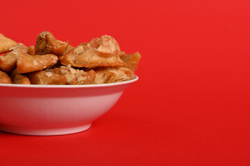Isolated studio shot on red background of cropped plate with delicious Arabian Moroccan dessert for religious events on a plate